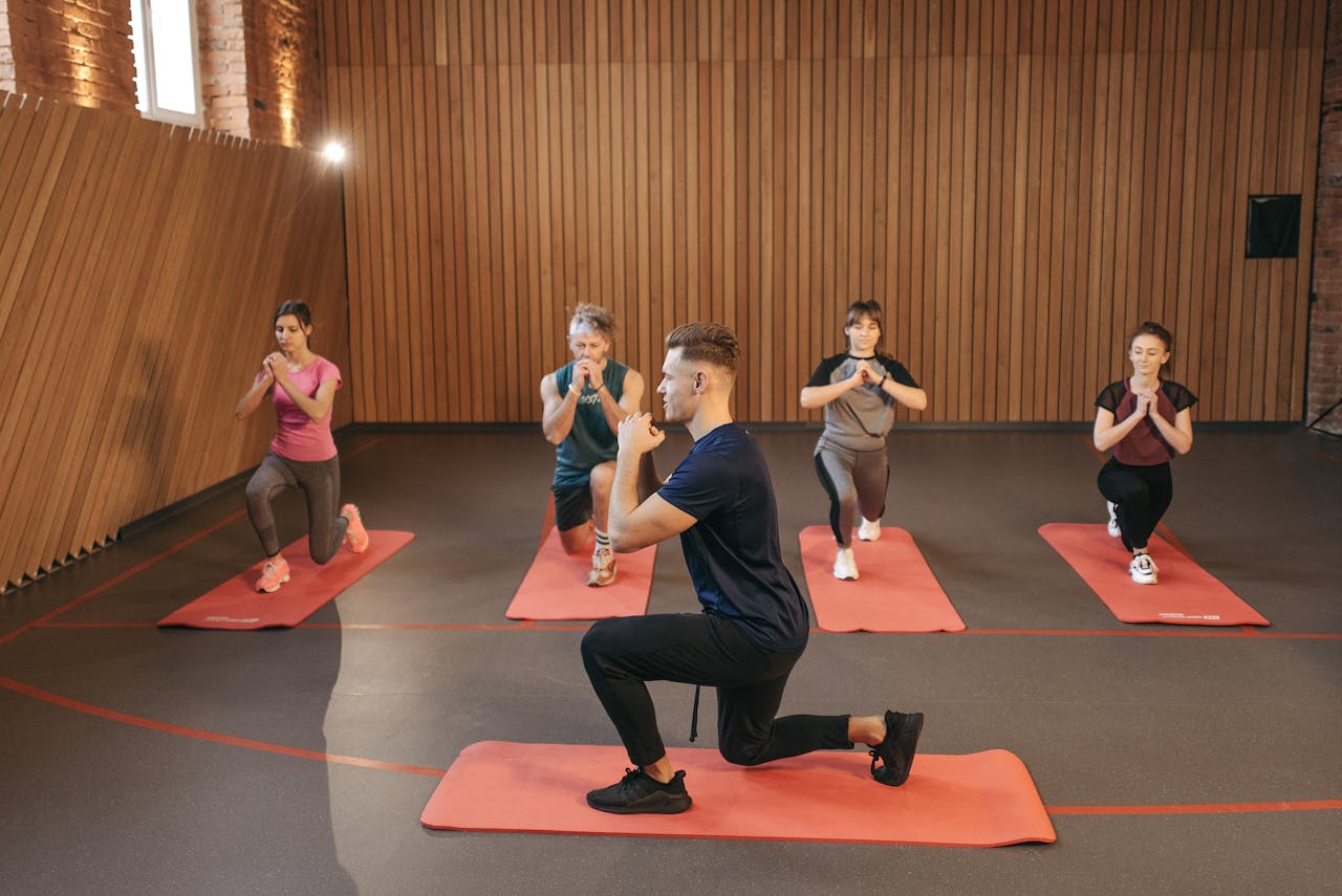 our-story A diverse group practicing fitness and yoga exercises indoors with mats.